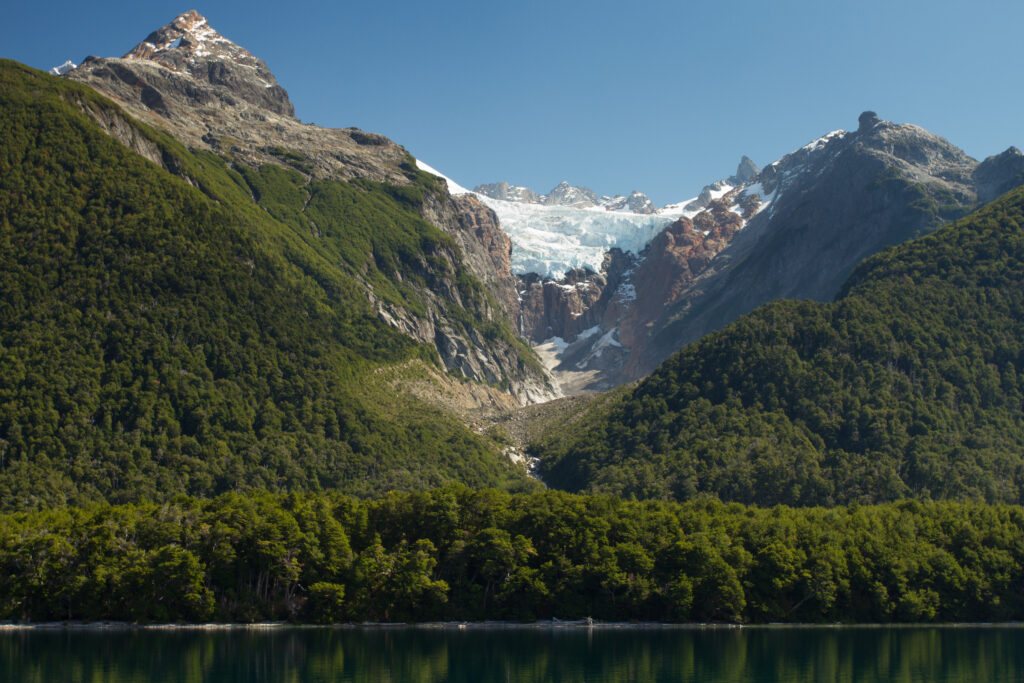 Valle con bosque y glaciar colgante sobre un lago