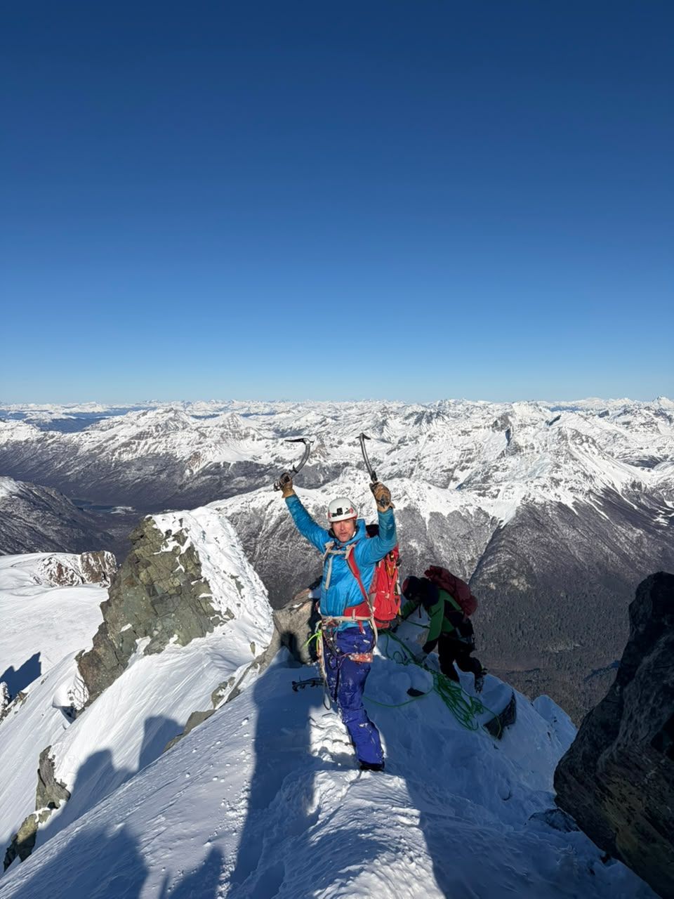 Cumbre nevada con los brazos en alto